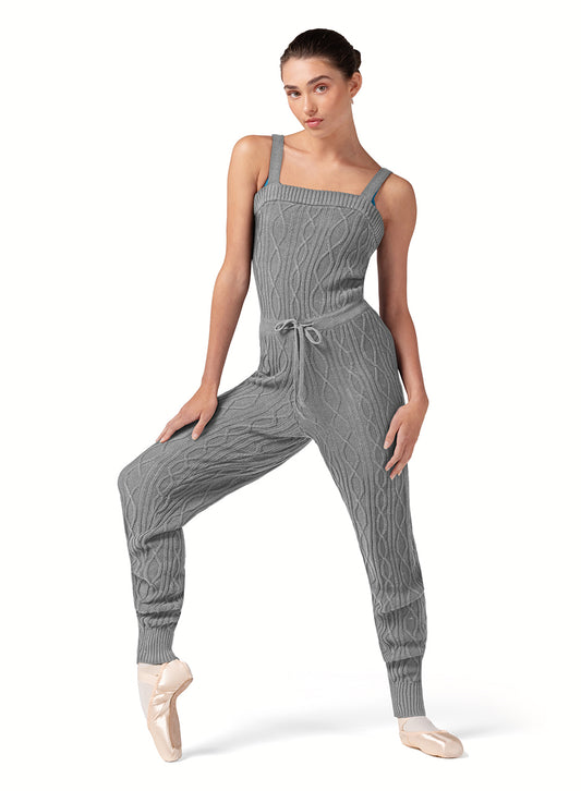 Dancer is wearing a grey marle, tank strap, square neck, cable knit, warm -up jumpsuit with a tie front waist. Dancer has paired the garment with pink tights and pointe shoes and has her right foot on pointe and right hand on her leg.