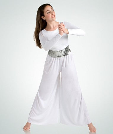 Dancer is wearing a white, long sleeve jumpsuit with a flared leg pant and back zipper closure. She has paired the garment with a wide, silver sequin belt and is standing in a prayer pose.