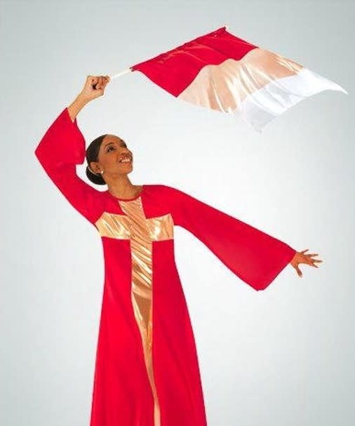 Dancer is wearing a long scarlet dress with pull over the head styling. Dress has semi bell sleeves and a metallic gold cross sewn into the fabric. Dancer is holding a scarlet, gold and white flag attached to a flag staff.