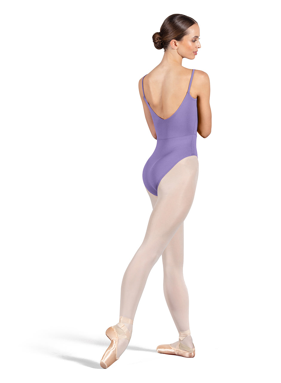 Dancer is wearing a lavender, camisole leotard with a scoop neck and back and bodice seam detail. She has paired the garment with pink tights and pointe shoes. Dancer is standing with her right foot pointed back and is showing a back angle of the leotard.