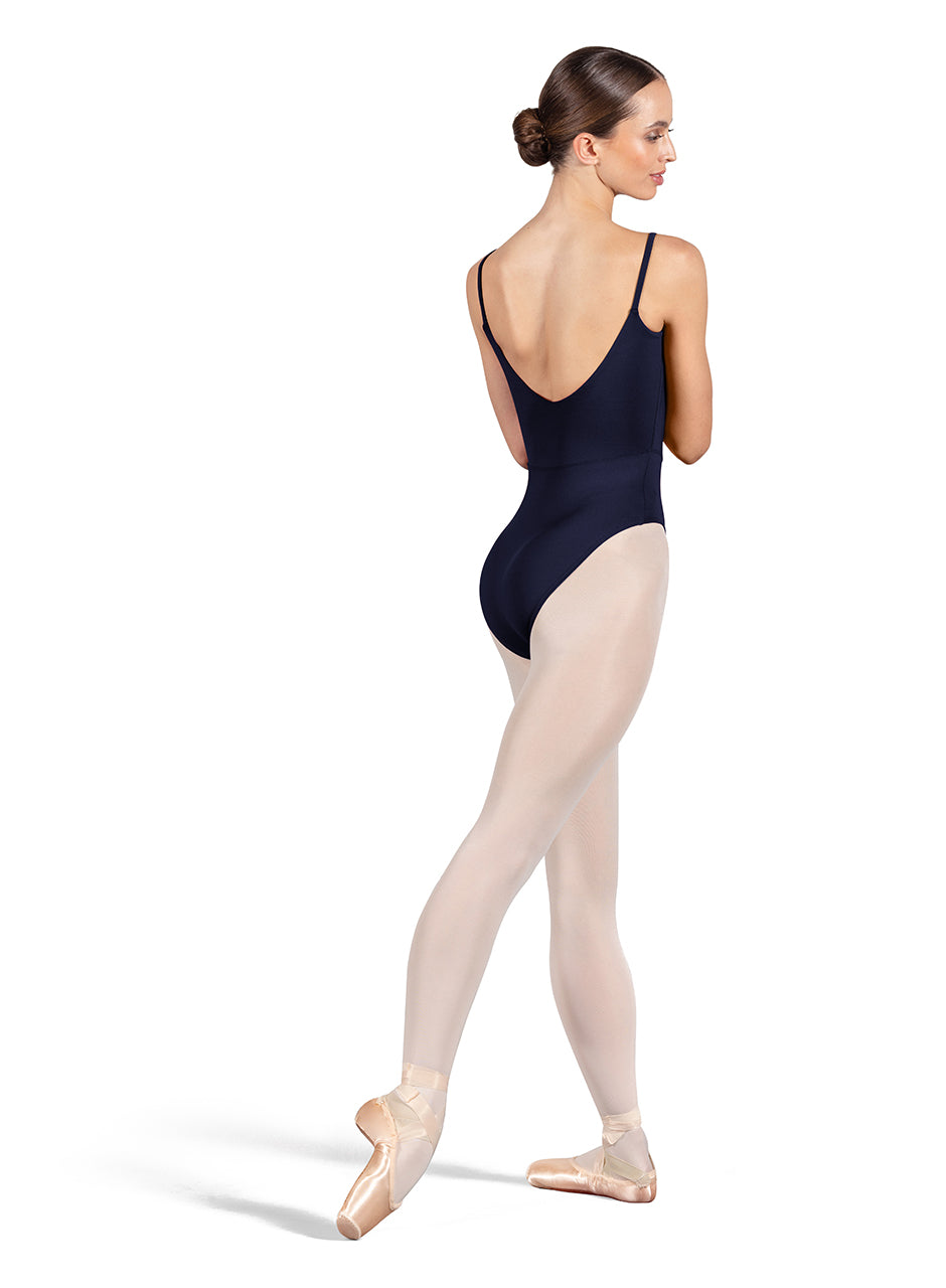 Dancer is wearing a navy blue, camisole leotard with a scoop neck and back and bodice seam detail. She has paired the garment with pink tights and pointe shoes. Dancer is standing with her right foot pointed back and is showing a back angle of the leotard.