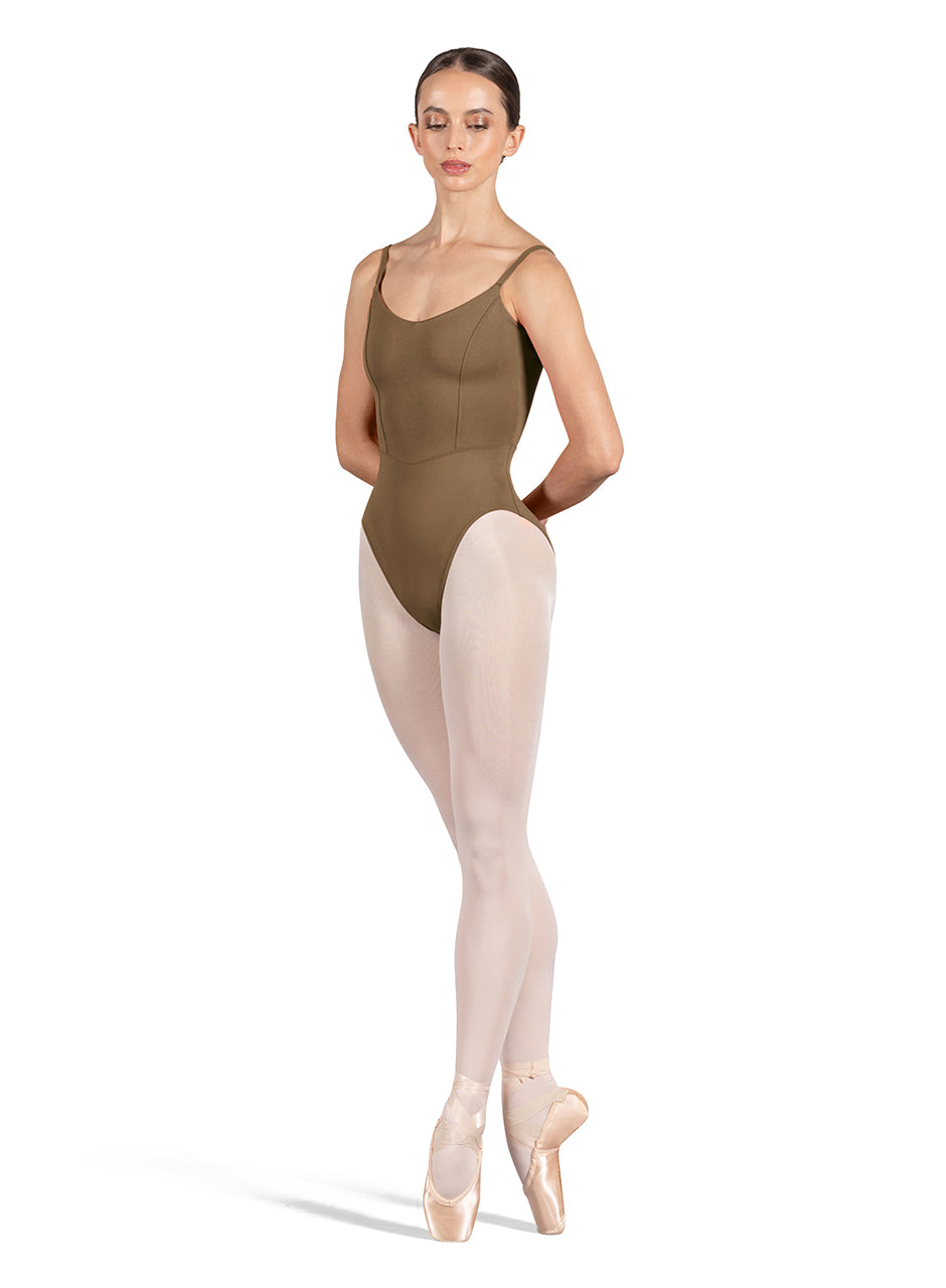 Dancer is wearing an almond, camisole leotard with a scoop neck and back and bodice seam detail. She has paired the garment with pink tights and pointe shoes and is balancing in a fourth position releve on pointe with her hands behind her back.