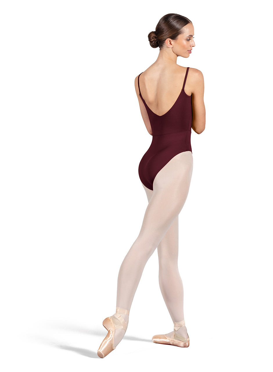 Dancer is wearing a burgundy, camisole leotard with a scoop neck and back and bodice seam detail. She has paired the garment with pink tights and pointe shoes. Dancer is standing with her right foot pointed back and is showing a back angle of the leotard.