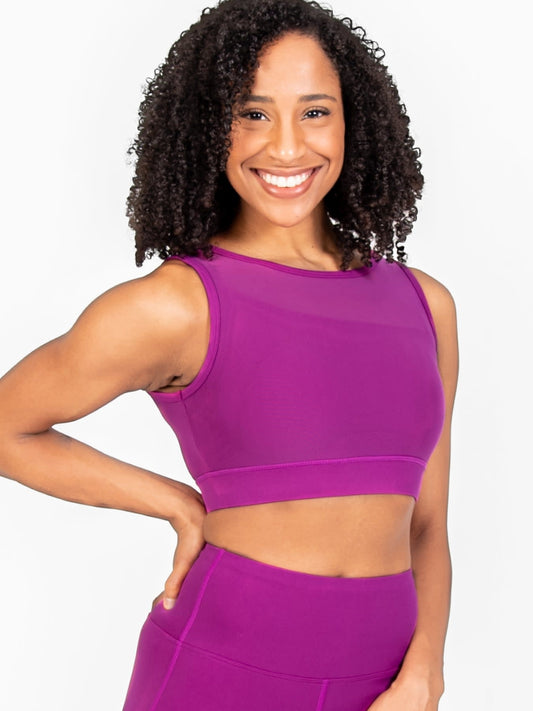 Dancer is wearing a double layer, tank style bra top with a mesh insert in the color Berry. She has paired the top with matching leggings.